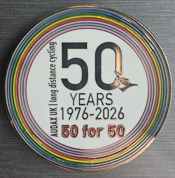 Audax UK 50th anniversary pin displaying ‘50 YEARS 1976–2026’ in black lettering surrounded by rainbow-coloured rings, with ‘50 for 50’ text beneath.